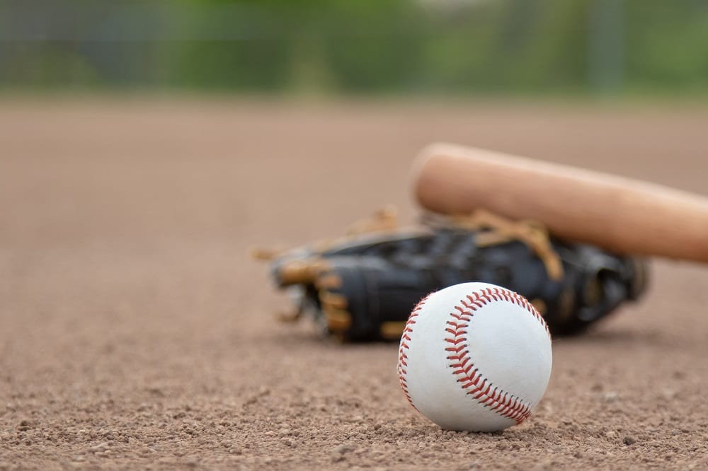 A baseball, glove and bat on a baseball field | Investment U