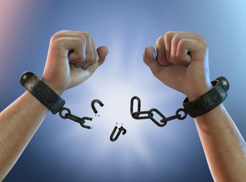 Two hands breaking handcuffs celebrating their newfound financial independence | Investment U