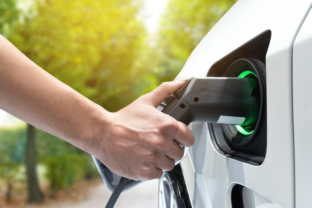 A hand charging an electric vehicle representing a great stock opportunity