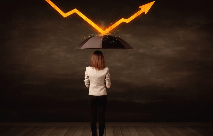 A woman holds up an umbrella to minimize her risk. How does diversification protect investors from risk?