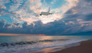 Image of an airplane flying over a beach. Are airline stocks a good choice in today’s market?