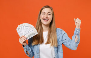 A young woman learning how to save money in your 20s holding cash.