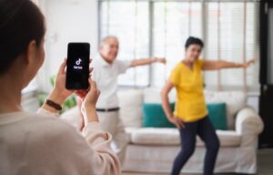 A girl recording two people making a tiktok video on here phone. Will Oracle acquire TikTok?