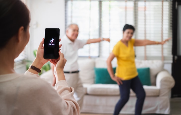 A girl recording two people making a tiktok video on here phone. Will Oracle acquire TikTok?