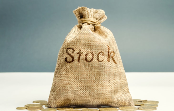 A bag of money with the word stock on it sitting on top of some coins.