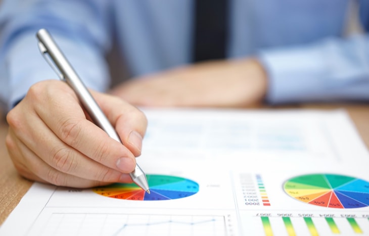 A man writes on his stock portfolio sheets to calculate the right position sizing.