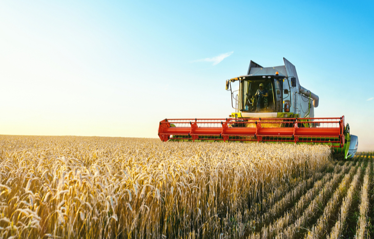 tractor harvesting grain and looking for the best agriculture stocks